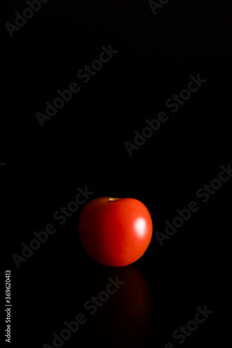 Tableau sur toile Vertical shot of a tomato on a black surrounding