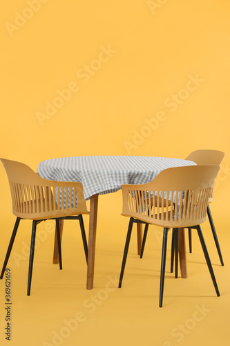 Dining table with chairs on color background