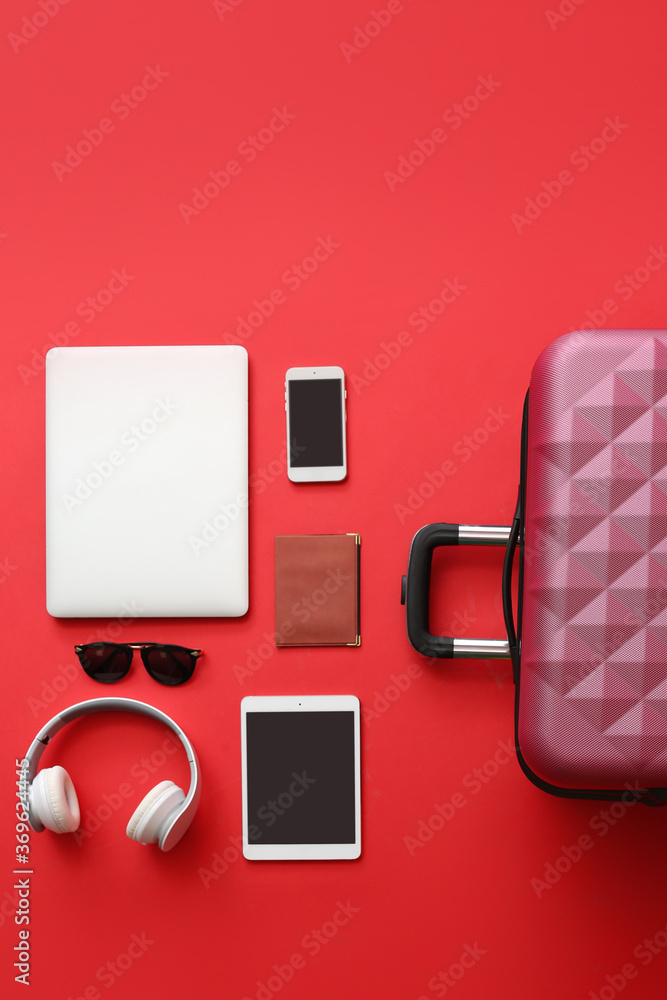 Packed suitcase with accessories and devices on color background. Travel concept - obrazy, fototapety, plakaty 