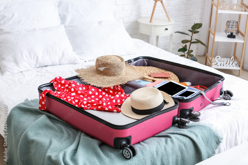 Packed suitcase with beach accessories on bed. Travel concept - obrazy, fototapety, plakaty 