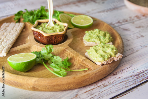 green guacamole on the wooden table with toasts