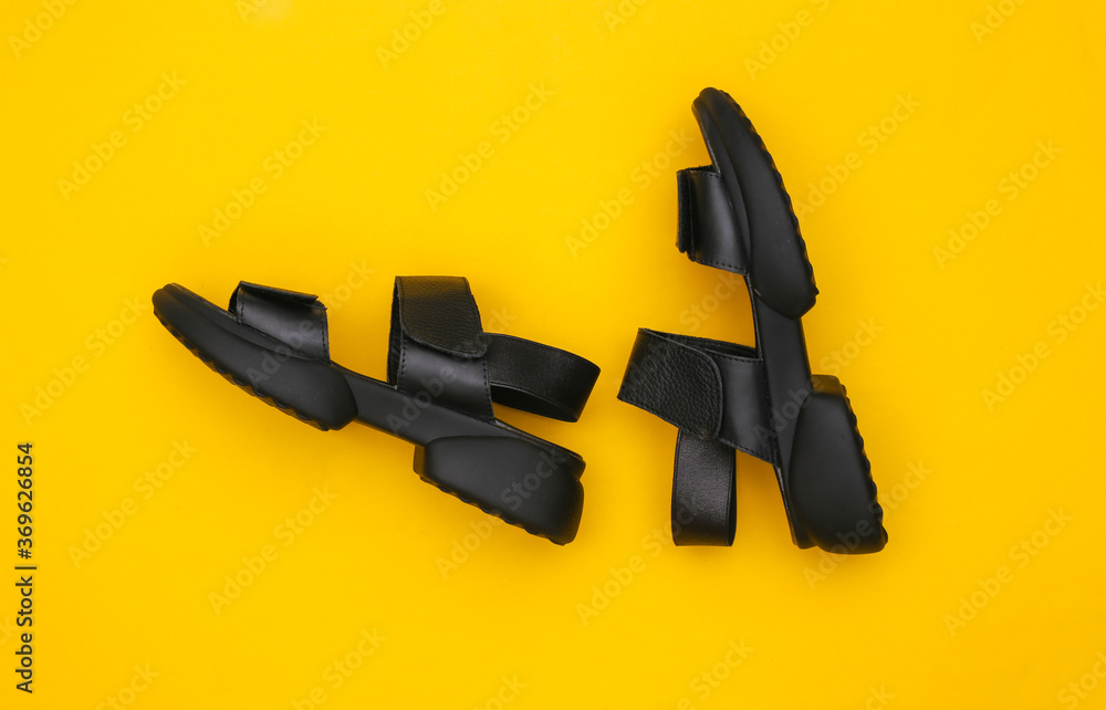 Leather black women's sandals on a yellow background. Top view. Flat lay Leather black women's sandals on a yellow background. Top view. Flat lay