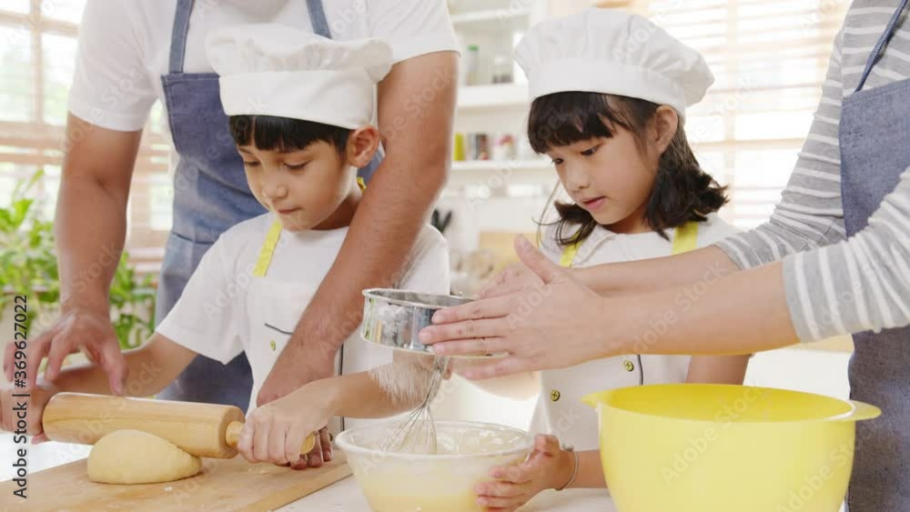 Happy smiling young Asian Japanese family with preschool kids have fun cooking baking pastry or pie for breakfast meal in modern kitchen home in the morning. Doing bakery knead dough and bake cookies. Happy smiling young Asian Japanese family with preschool kids have fun cooking baking pastry or pie for breakfast meal in modern kitchen home in the morning. Doing bakery knead dough and bake cookies.