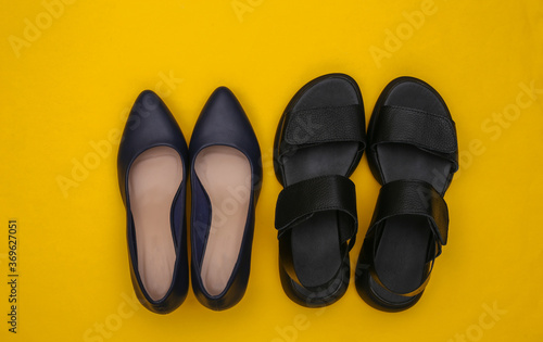 Leather women's sandals and high heel shoes on yellow background. Top view. Flat lay