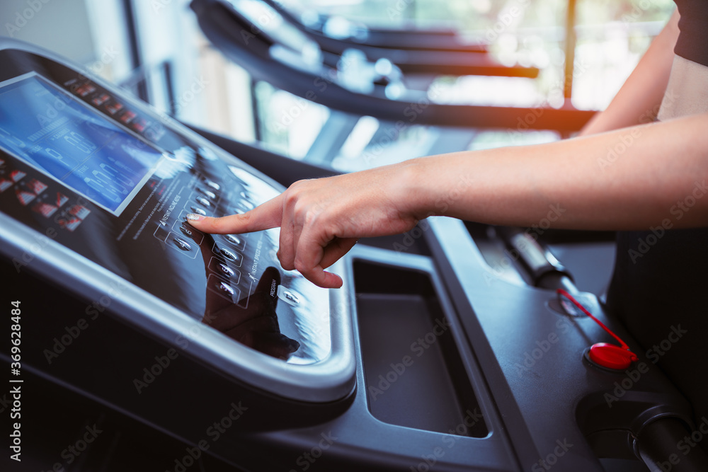 close up hand women point to button control speed treadmill in fitness center, set up program before workout.