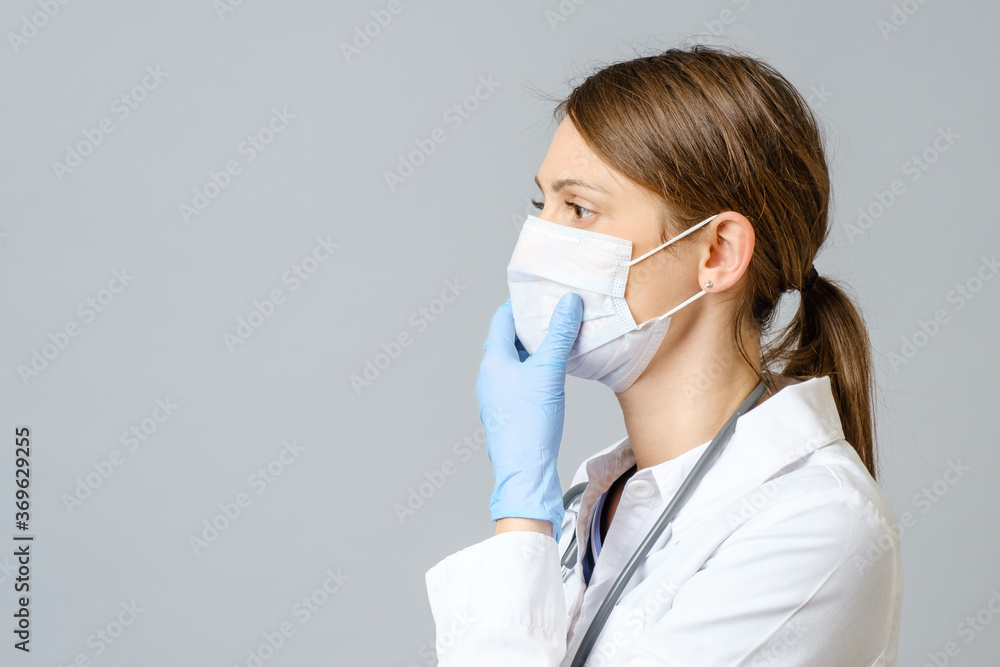 Portrait of doctor putting sterile mask isolated on gray Portrait of doctor putting sterile mask isolated on gray
