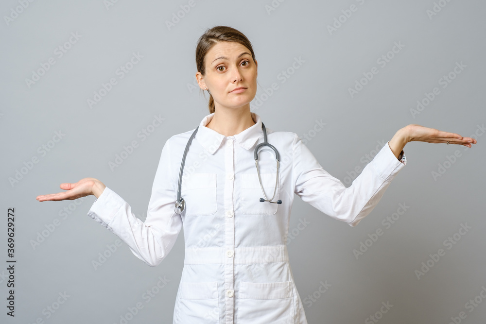 Portrait of woman doctor shrugging shoulders isolated on gray Portrait of woman doctor shrugging shoulders isolated on gray