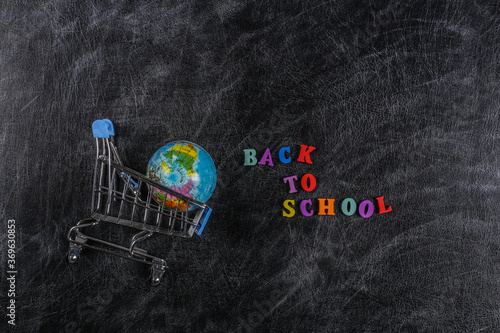 Preschool shopping. Supermarket trolley with globe on chalk board with text Back to School.