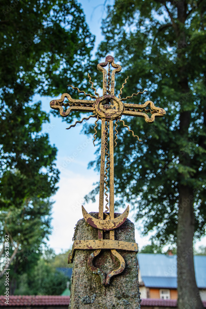 old metal cross, trees and sky in the background