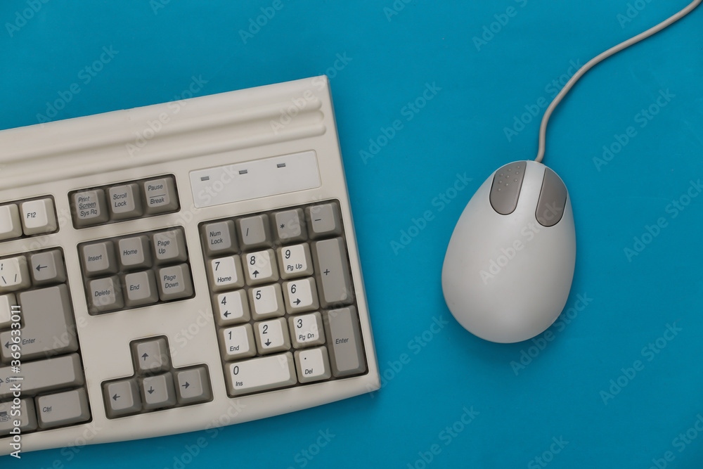 Old keyboard and pc mouse on a blue background. Top view. Flat lay Old keyboard and pc mouse on a blue background. Top view. Flat lay