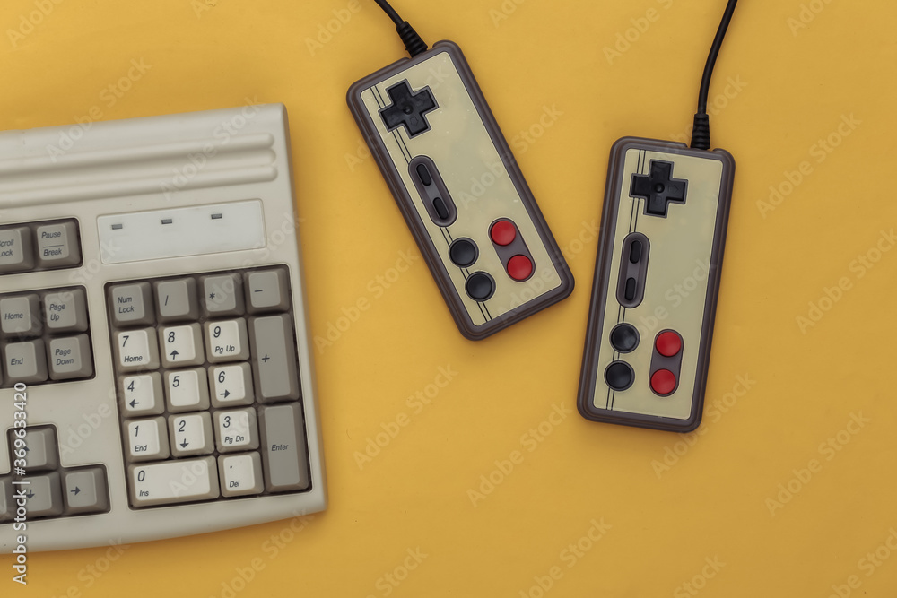 Old pc keyboard and gamepads on yellow background. Retro gaming. Video game, 80s. Top view. Flat lay Old pc keyboard and gamepads on yellow background. Retro gaming. Video game, 80s. Top view. Flat lay