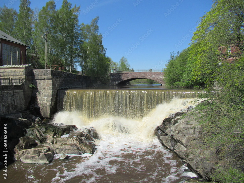 Water streaming through a historical small water power plant with red brick buildings. Water streaming through a historical small water power plant with red brick buildings.