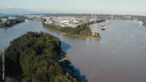 Aerial Fly over an island indangered wild life in the midst of big industry import export harbor for freighters barges cargo for natural resources hemp lumber produce canibas a river ocean connect 2-3 photo