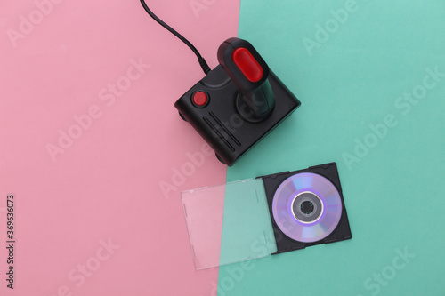 Retro joystick and CD in box on pink blue pastel background. Gaming, video game competition