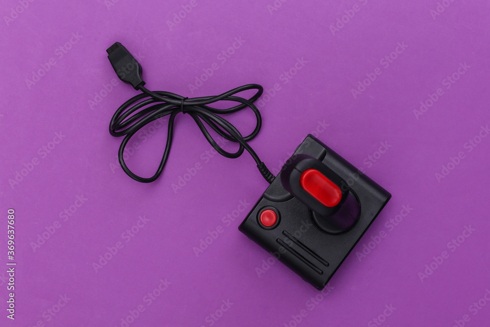 Wired retro joystick with wound cable on purple background. Video game, gaming. Top view Wired retro joystick with wound cable on purple background. Video game, gaming. Top view