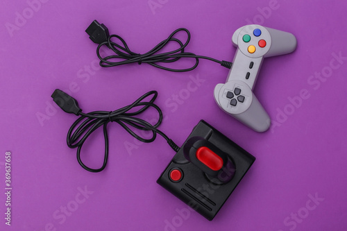 Wired retro gamepad and joystick with wound cable on purple background. Video game, gaming. Top view