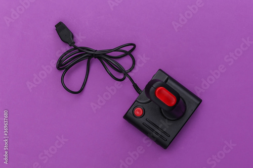 Wired retro joystick with wound cable on purple background. Video game, gaming. Top view