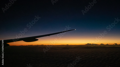 The view of airplane wing with beautiful sunrise at horizon sky background.