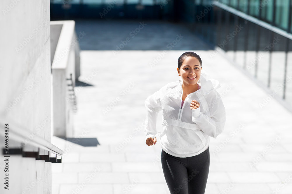 fitness, sport and healthy lifestyle concept - happy smiling young african american woman running upstairs outdoors fitness, sport and healthy lifestyle concept - happy smiling young african american woman running upstairs outdoors