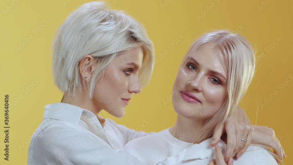 Adorable tender lgbt couple family posing together in the studio. Sensual cute girlfriends exchange hugs kiss enjoying each other. Female portrait. Adorable tender lgbt couple family posing together in the studio. Sensual cute girlfriends exchange hugs kiss enjoying each other. Female portrait.