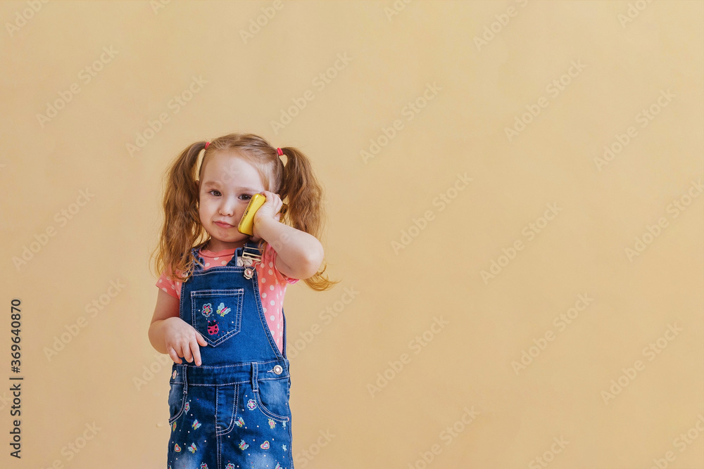 Cute little girl is talking on cell phone
on a yellow background. Copy space Cute little girl is talking on cell phone
on a yellow background. Copy space