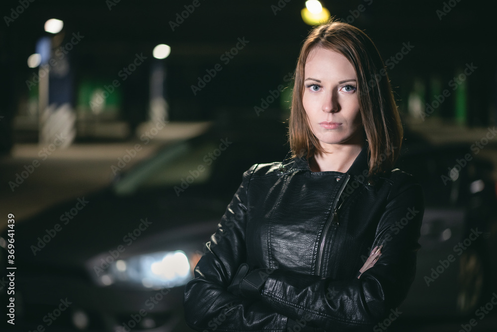 Fototapeta premium A young pretty girl is standing on a car background.