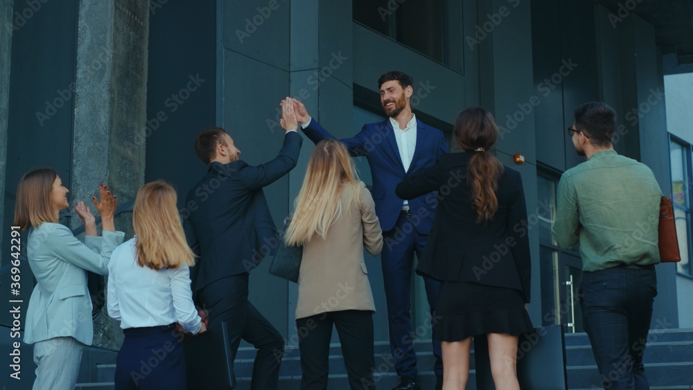 Obraz premium Happy group of office workers employees being motivated by handsome boss speech. Business team. Teambuilding. Power of partnership. Corporate staff.