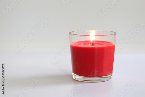 red candle in glass on white table and background