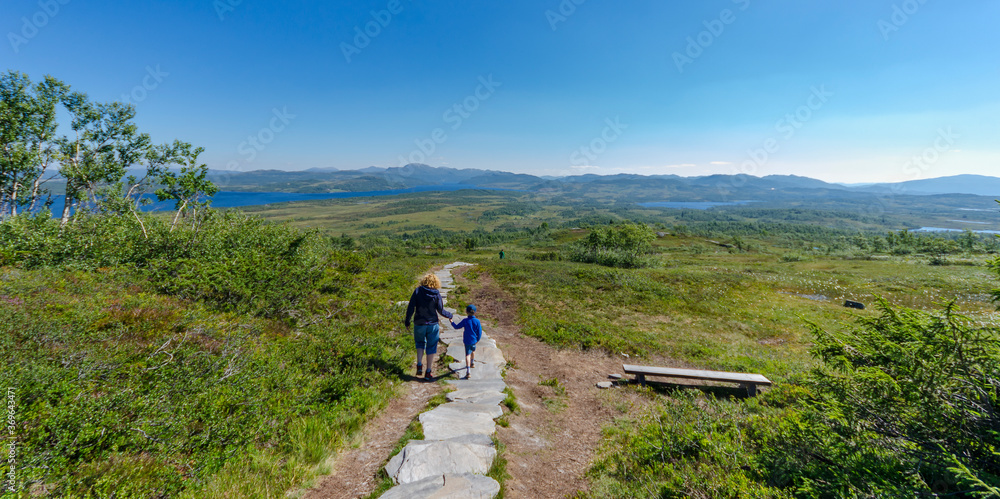Mother and son walk down a mountain path in the Norwegian mountains