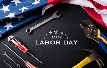 Happy Labor day concept. American flag with different construction tools on black table background, with copy space for text.