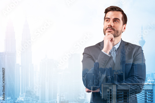 Young handsome businessman in suit with hand on chin thinking how to succeed, new career opportunities, MBA. Kuala Lumpur on background. Double exposure. photo