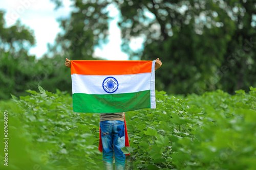 Indian child celebrating Independence or Republic day, Cute little Indian child holding, waving or running with Tricolour flag with greenery in the background,