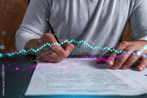 Double exposure of man signing contract and forex graph hologram. Blue infographic business chart. Concept of market investment.