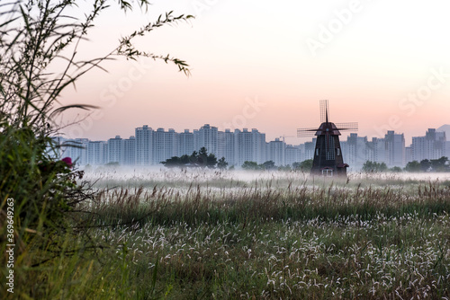 Scenery view windmill landscape surrounded by fog during morning haze at dawn, wetland ecological grand park.