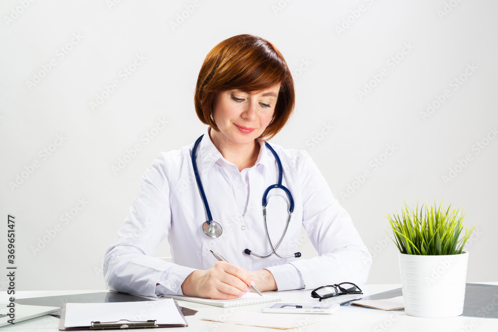 Beautiful doctor sitting in office and writing Beautiful doctor sitting in office and writing