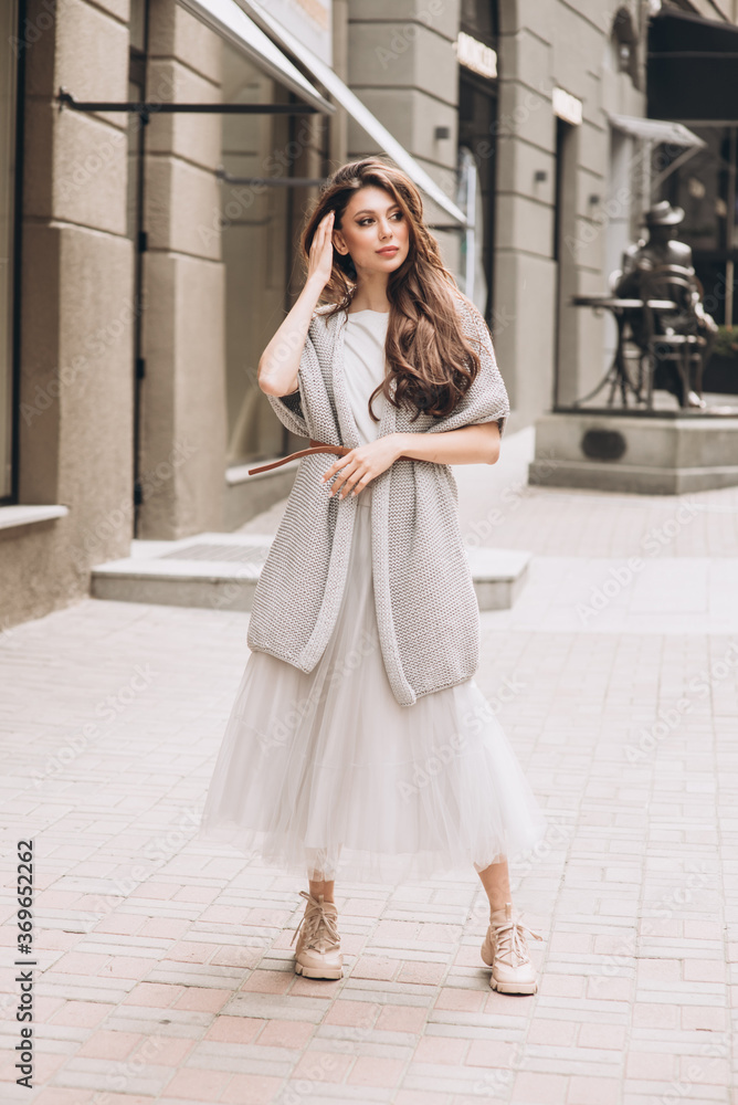 Young girl in white clothes goes on a street. Street style. Soft selective focus.