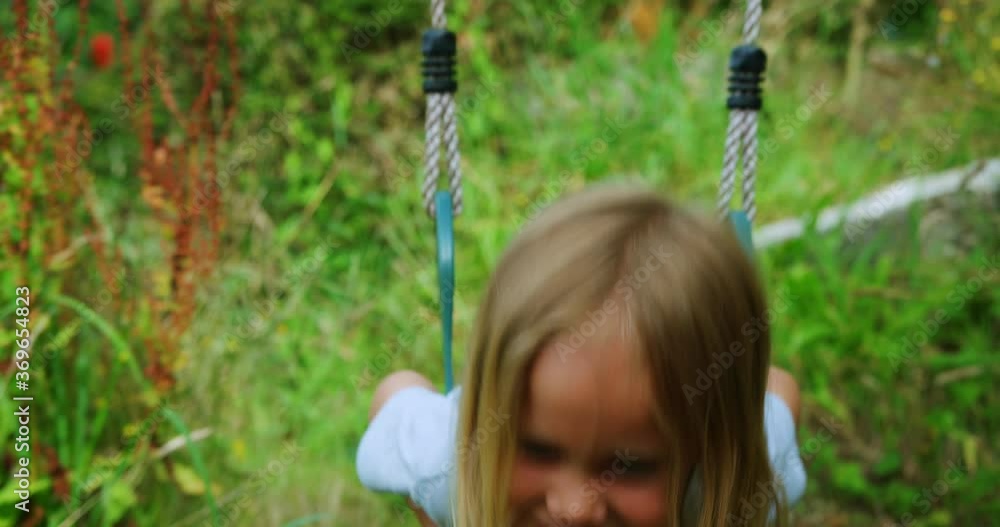 Preschooler playing on a swing in the garden Preschooler playing on a swing in the garden