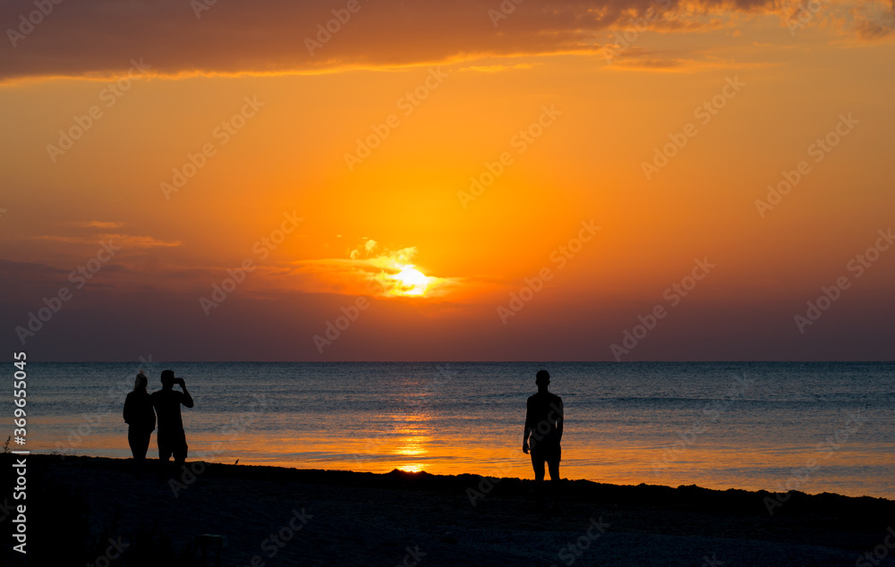 Sunrise by the sea. People admire the sunrise on the beach