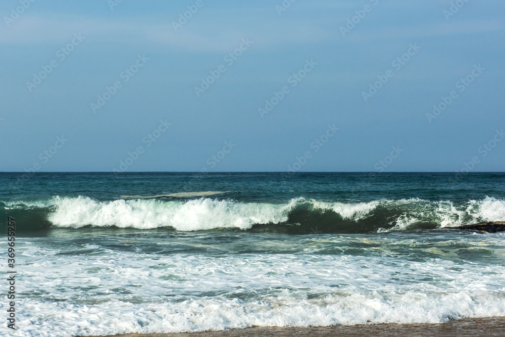 The big breaking waves during a strom at the beautiful summer sea shore background the blue sky and horizon