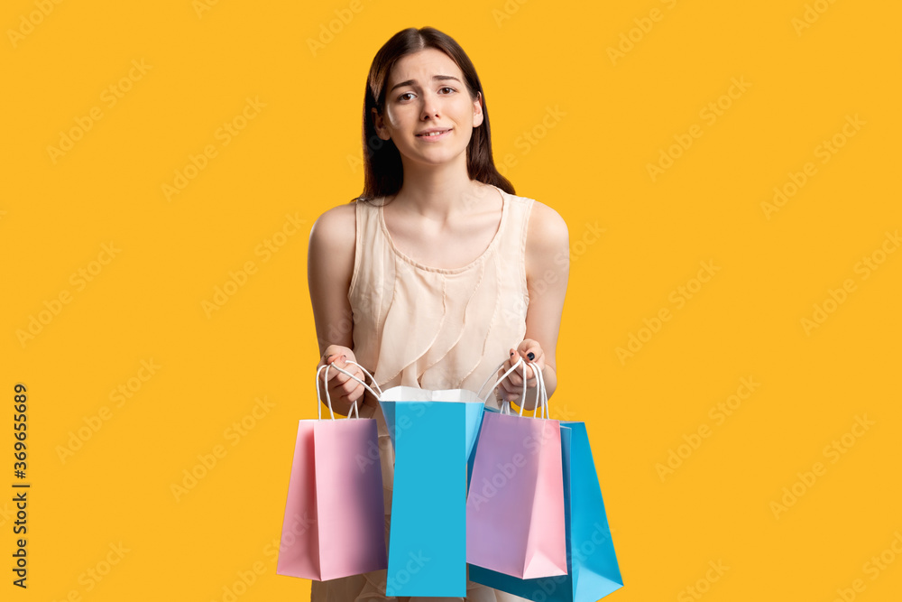 Disappointed shopper. Online shopping. Sad woman with paper bags isolated on orange. Dislike purchase. Wrong order Disappointed shopper. Online shopping. Sad woman with paper bags isolated on orange. Dislike purchase. Wrong order