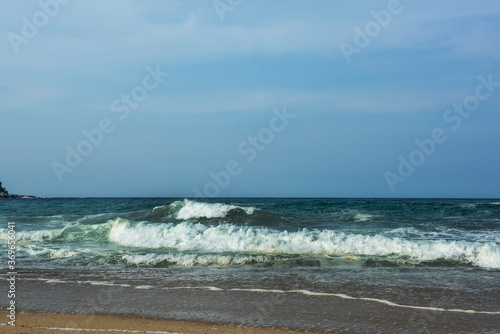 The huge waves crashing into ston island against the blue sky and horizon at summer sea shore.