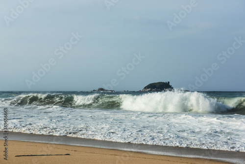 The huge waves crashing into ston island against the blue sky and horizon at summer sea shore.