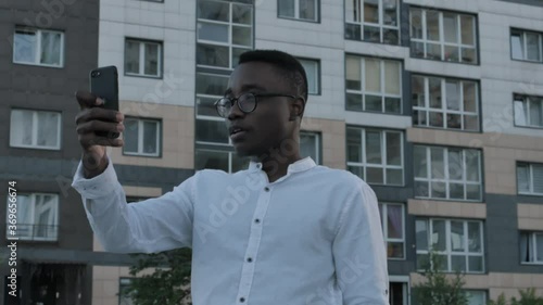 Wallpaper Mural Handsome happy smiling young black man talking on video on tablet phone outdoors. Portrait of african businessman waving to camera while videochatting on device, having conversation Torontodigital.ca