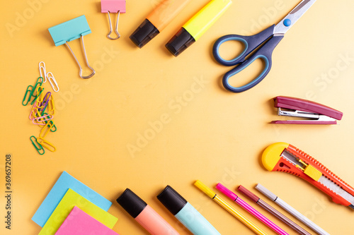 different stationary items on yellow background as studying or schooling or office concept