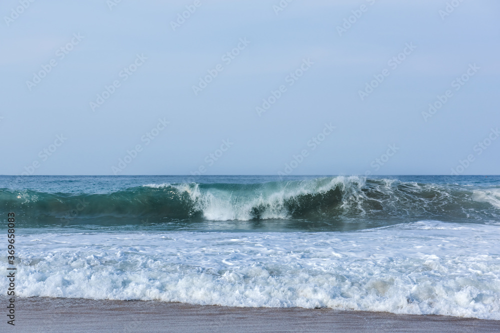 The huge waves crashing into ston island against the blue sky and horizon at summer sea shore. The huge waves crashing into ston island against the blue sky and horizon at summer sea shore.