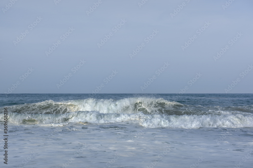 The huge waves crashing into ston island against the blue sky and horizon at summer sea shore. The huge waves crashing into ston island against the blue sky and horizon at summer sea shore.