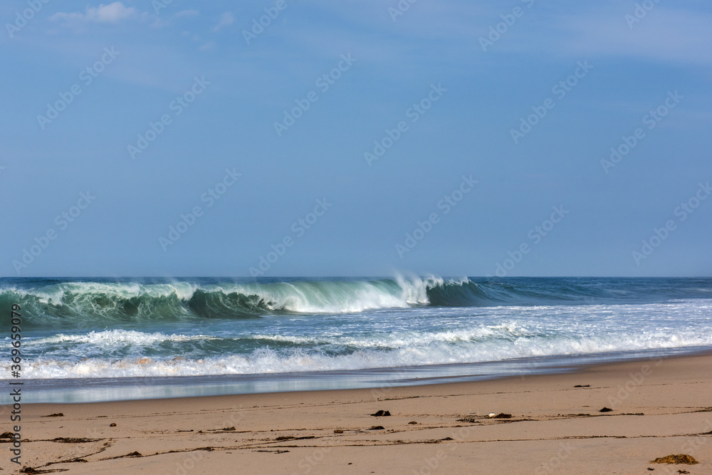 The huge waves crashing into ston island against the blue sky and horizon at summer sea shore.