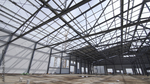 Construction of modern factory or warehouse, modern industrial exterior, panoramic view. Modern storehouse construction site, structural steel structure of new commercial building