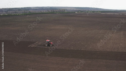 Drone footage of tractor plows field, prepares for crops. dust on field. Tractor plowing the dusty arid soil. Cultivator plows the land, working in a field. Sowing agricultural crops at field