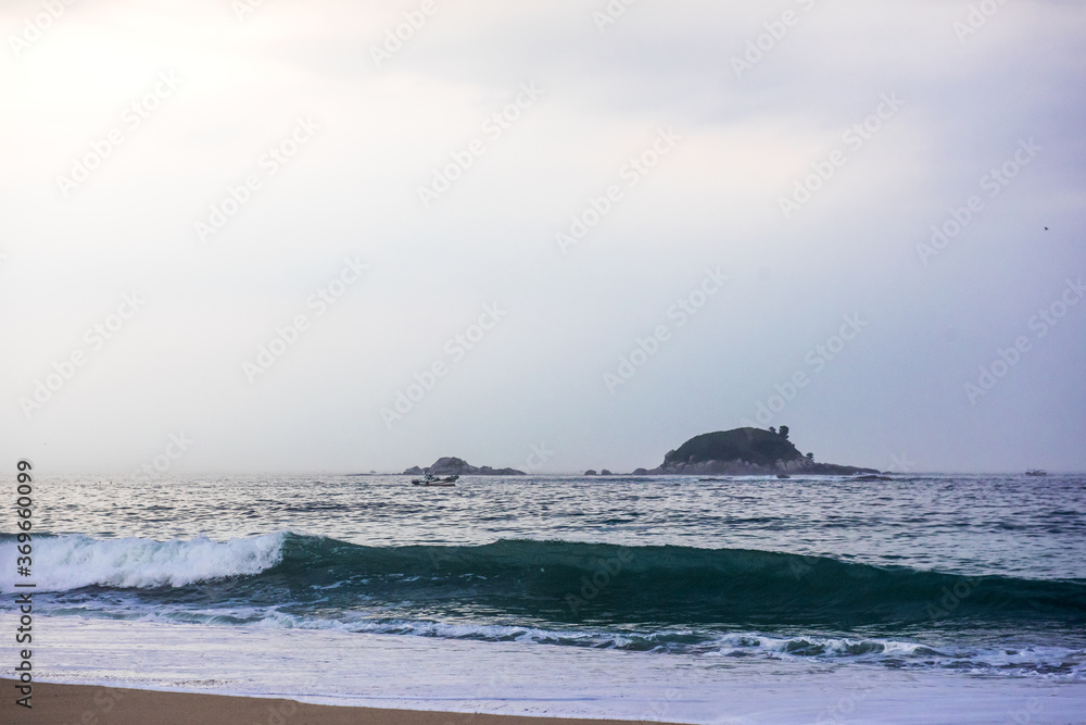 The huge waves crashing into ston island against the blue sky and horizon at summer sea shore. The huge waves crashing into ston island against the blue sky and horizon at summer sea shore.